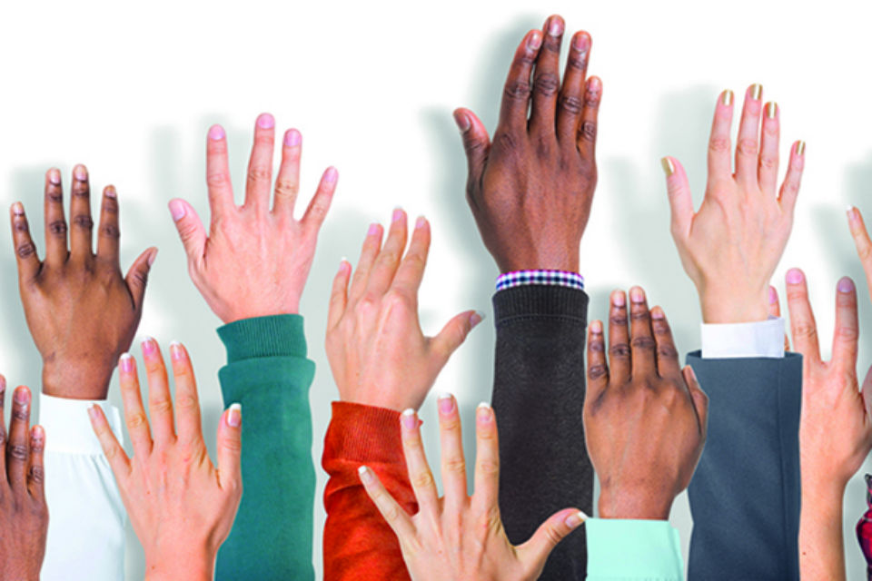 Photo of lots of people's hands being held up in the air, volunteering for stuff