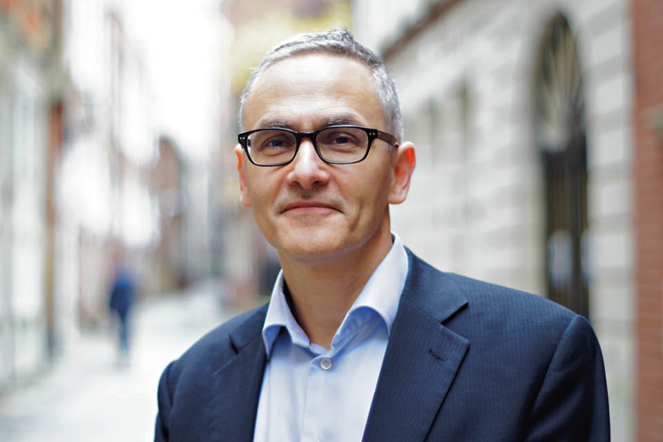 Head and shoulders of bespectacled man wearning blue shirt and jacket