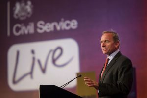 Man speaking at lectern with graphics behind