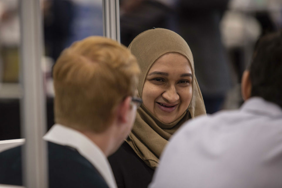 Woman in hijab, and two men at conference