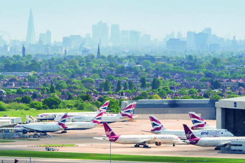 Birds-eye view of British Airways planes, and one Virgin airliner, at Heathrow airport, with London skyline in the background