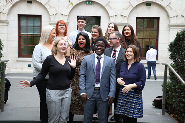 Photograph of the lead organiser of Civil Service Live in a ministry courtyard, surrounded by apprentices from various government departments who volunteered to work at Civil Service Live events in 2019