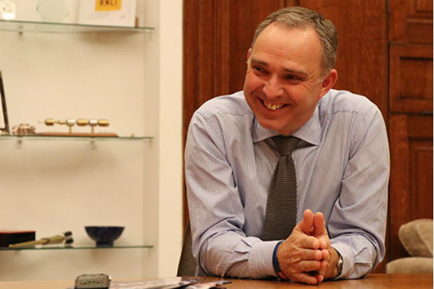 Image of Cabinet Secretary Mark Sedwill smiling and leaning forward on a table in his office