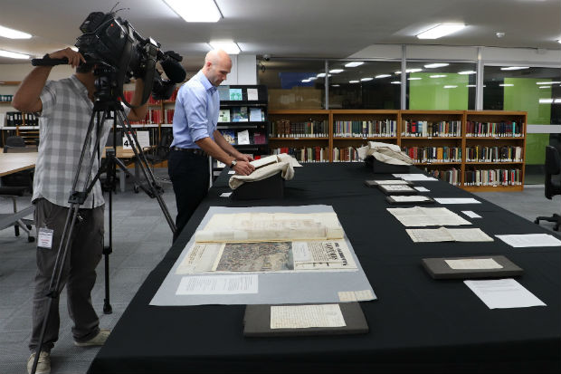 Staff at The National Archives photographing historical documents laid out on a table